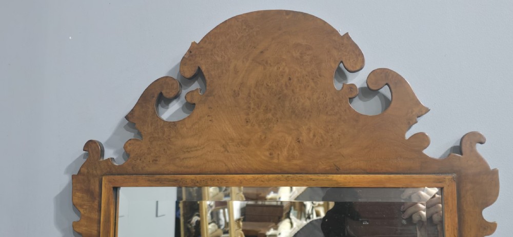 A vertical wall mirror featuring a carved burr walnut frame with scrollwork fretwork at the top crest and bottom apron. View V