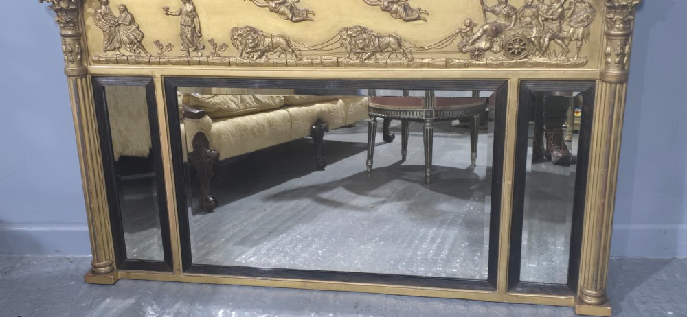 A wide Regency giltwood triple-plate overmantel mirror featuring a classical relief frieze depicting figures and chariot above fluted columns. View III