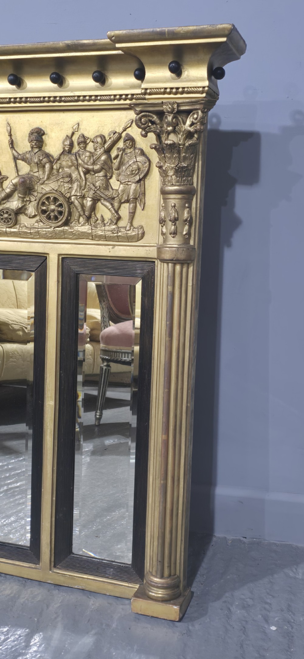 A wide Regency giltwood triple-plate overmantel mirror featuring a classical relief frieze depicting figures and chariot above fluted columns. View IV