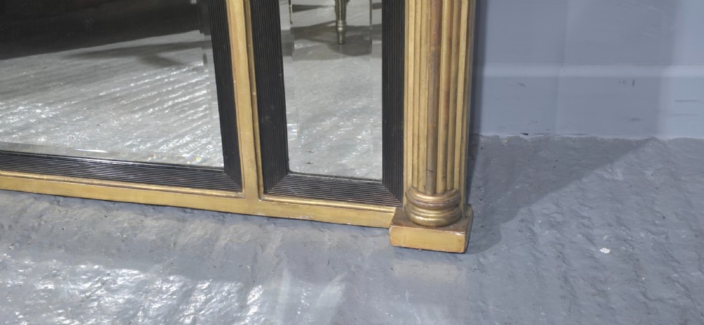 A wide Regency giltwood triple-plate overmantel mirror featuring a classical relief frieze depicting figures and chariot above fluted columns. View VII
