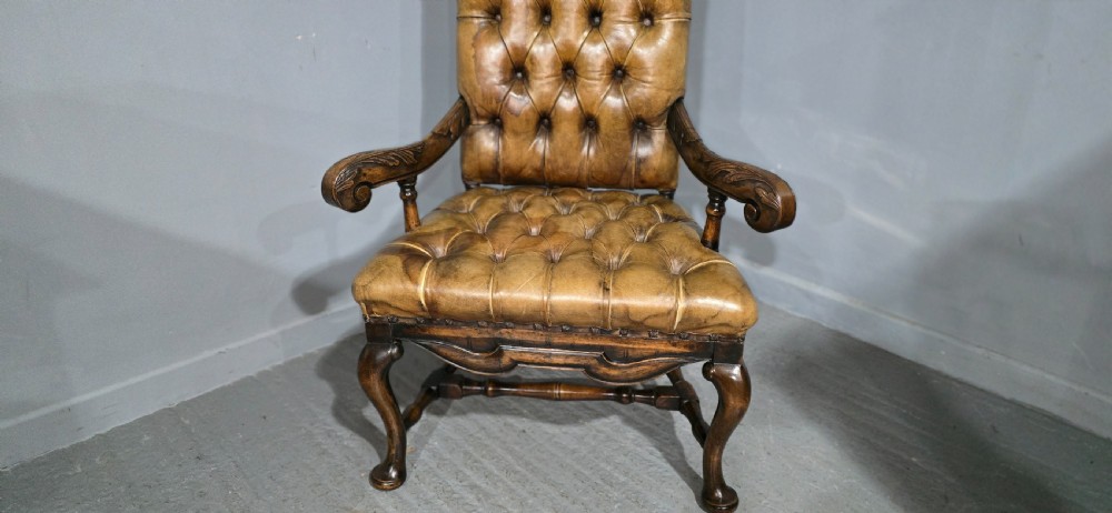 An antique William and Mary style high-back armchair upholstered in deep-buttoned tan leather with carved walnut arms and legs. View IV