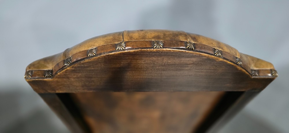 An antique William and Mary style high-back armchair upholstered in deep-buttoned tan leather with carved walnut arms and legs. View XIV