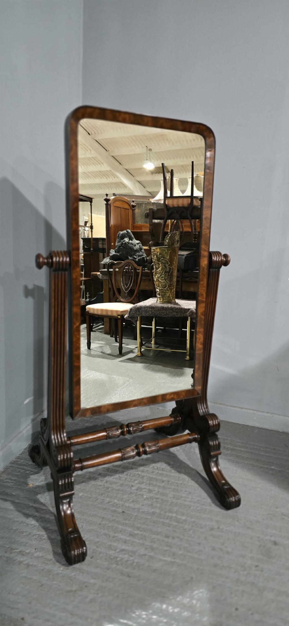 An antique Regency mahogany cheval mirror featuring a rectangular frame set between reeded upright posts on splayed legs. View III