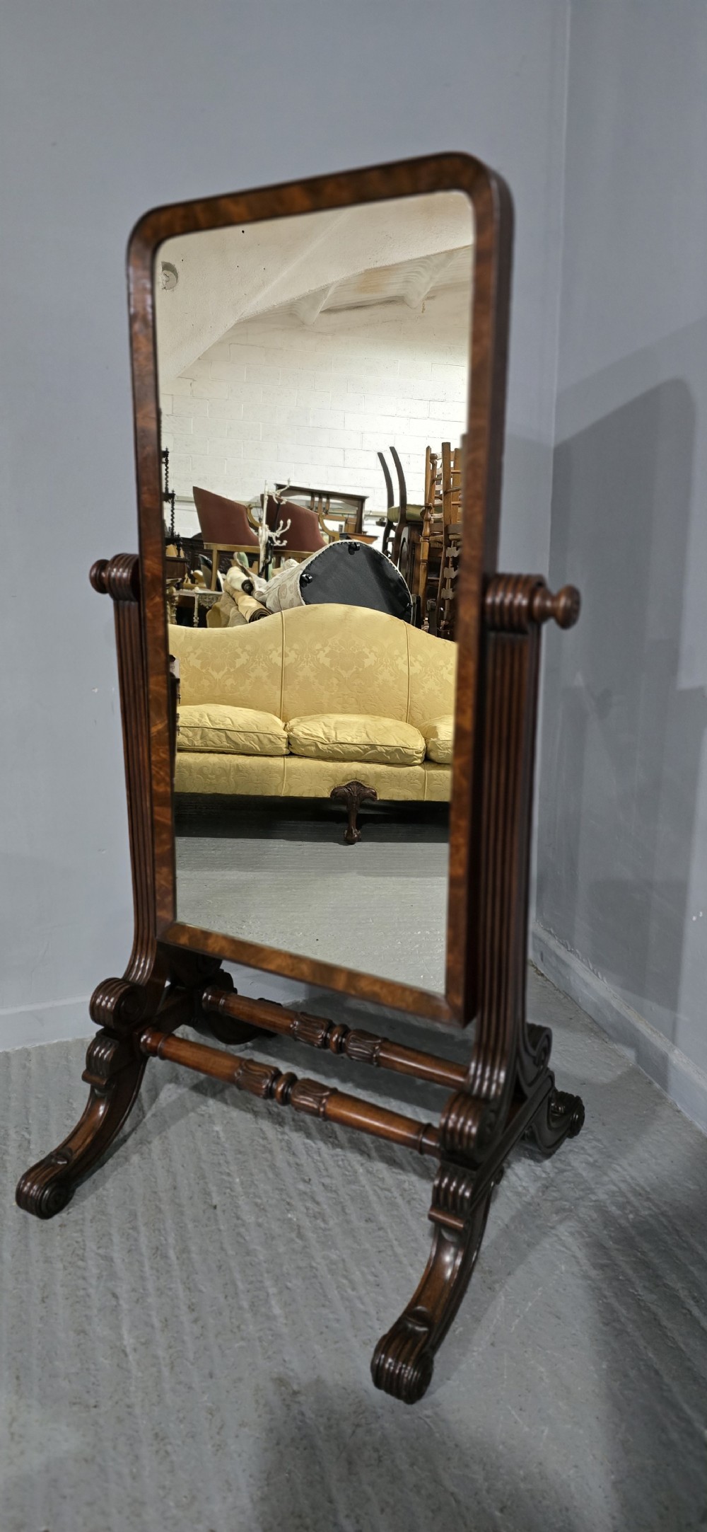 An antique Regency mahogany cheval mirror featuring a rectangular frame set between reeded upright posts on splayed legs. View IV
