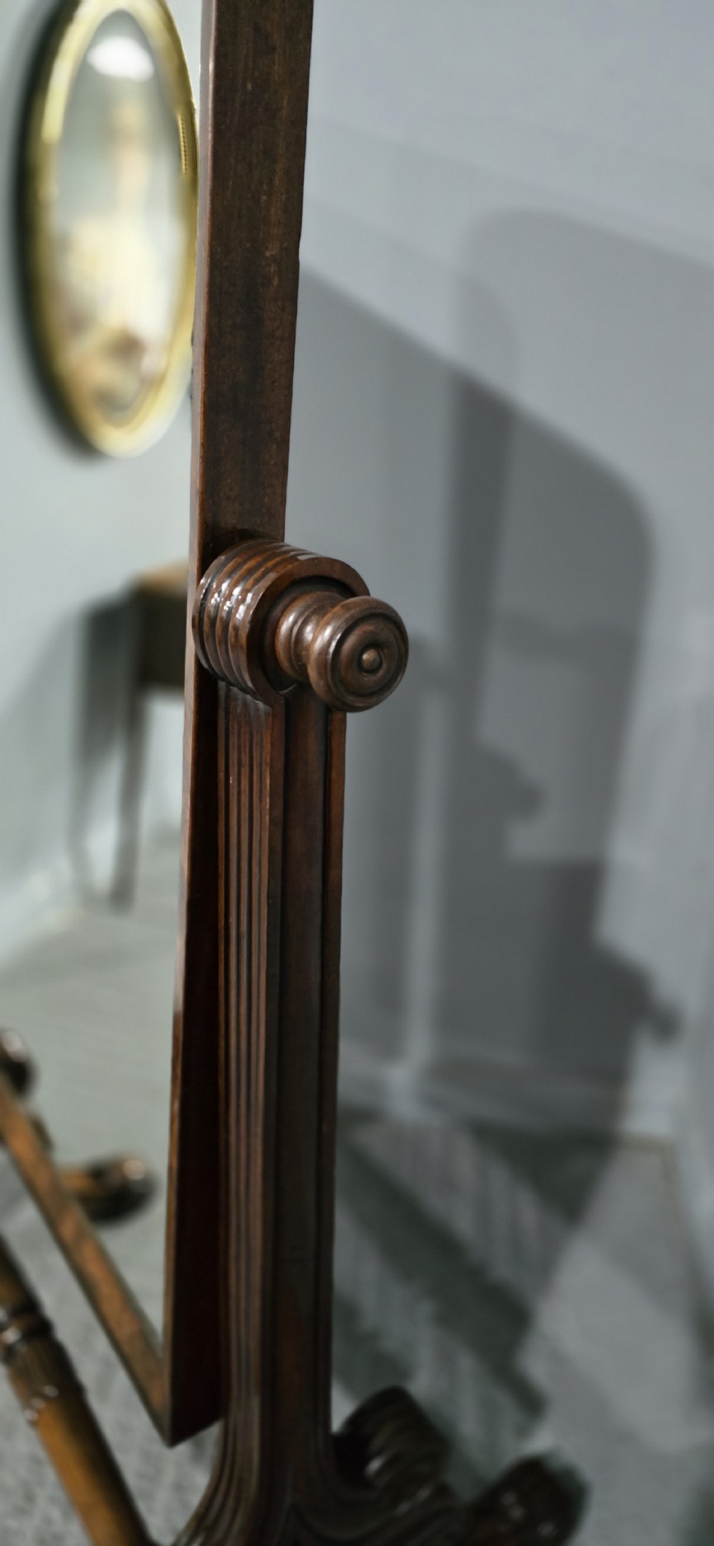 An antique Regency mahogany cheval mirror featuring a rectangular frame set between reeded upright posts on splayed legs. View VI