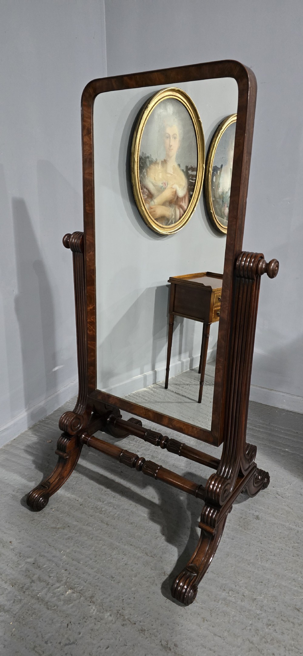 An antique Regency mahogany cheval mirror featuring a rectangular frame set between reeded upright posts on splayed legs. View XIV