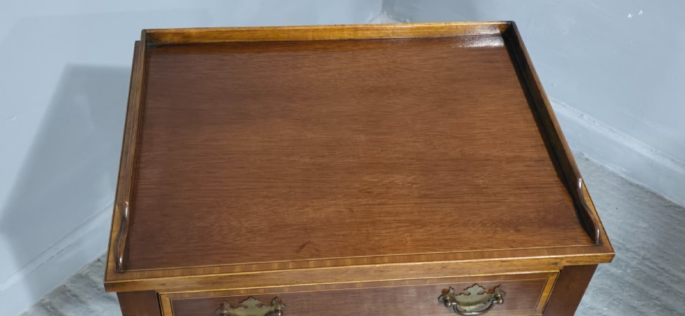 A dark mahogany side table featuring two drawers with brass batwing drop handles, crossbanded inlay borders, and slender turned legs. View IV