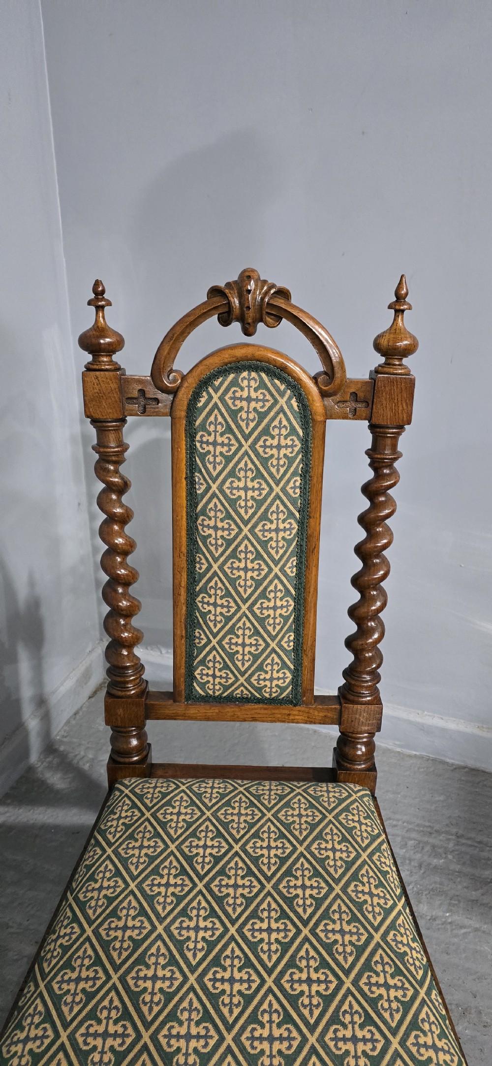 An antique walnut hall chair featuring spiral barley twist legs and supports, a carved crest with finials, and green patterned textile upholstery on the seat and backrest. View III