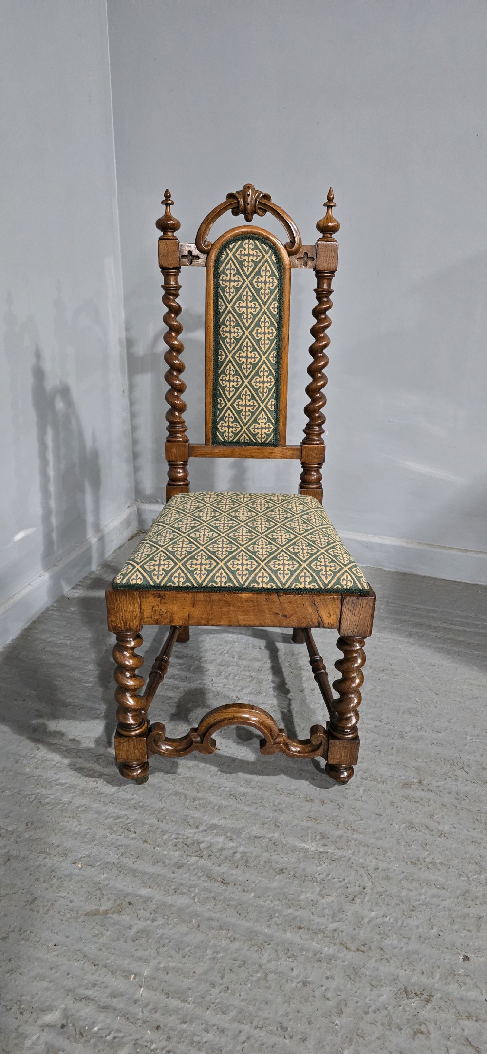 An antique walnut hall chair featuring spiral barley twist legs and supports, a carved crest with finials, and green patterned textile upholstery on the seat and backrest. View IV