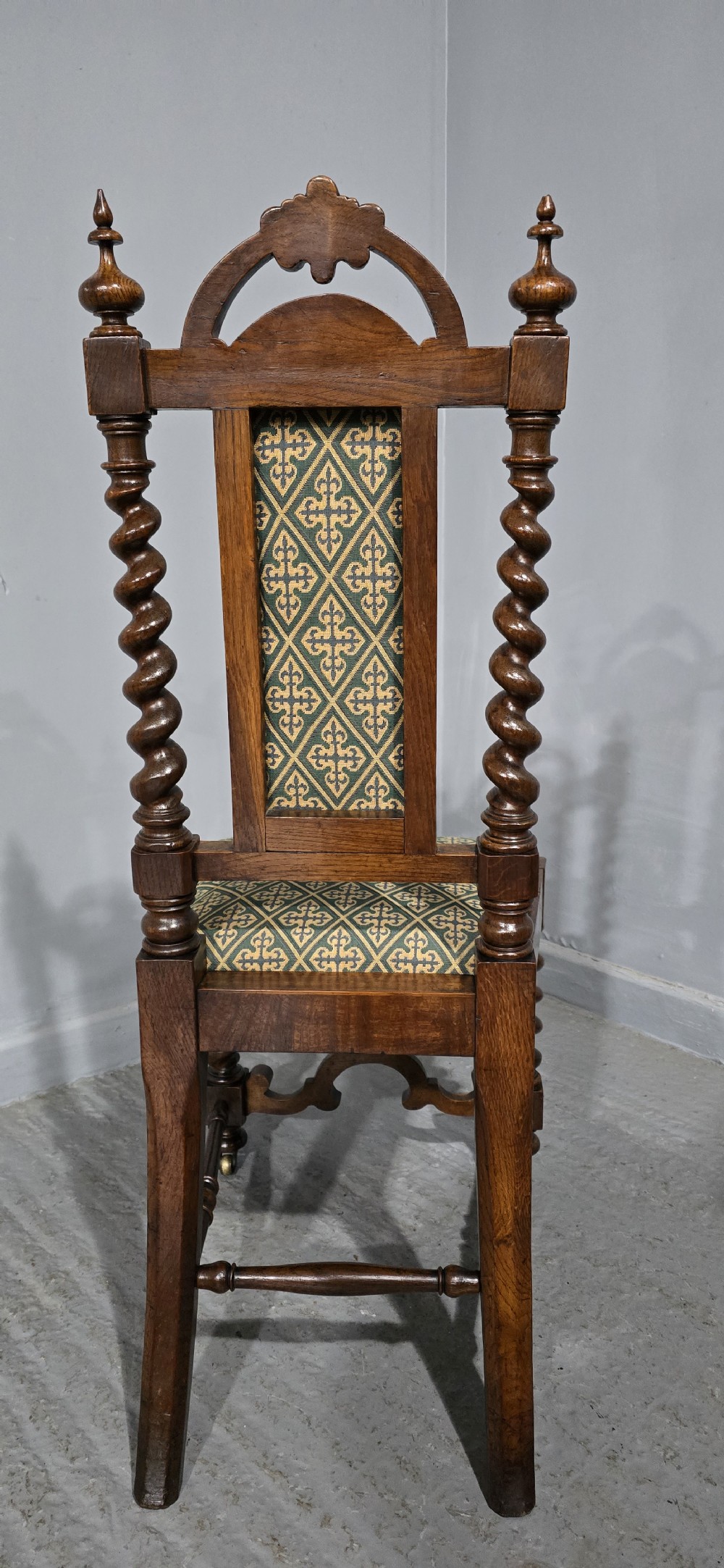 An antique walnut hall chair featuring spiral barley twist legs and supports, a carved crest with finials, and green patterned textile upholstery on the seat and backrest. View IX