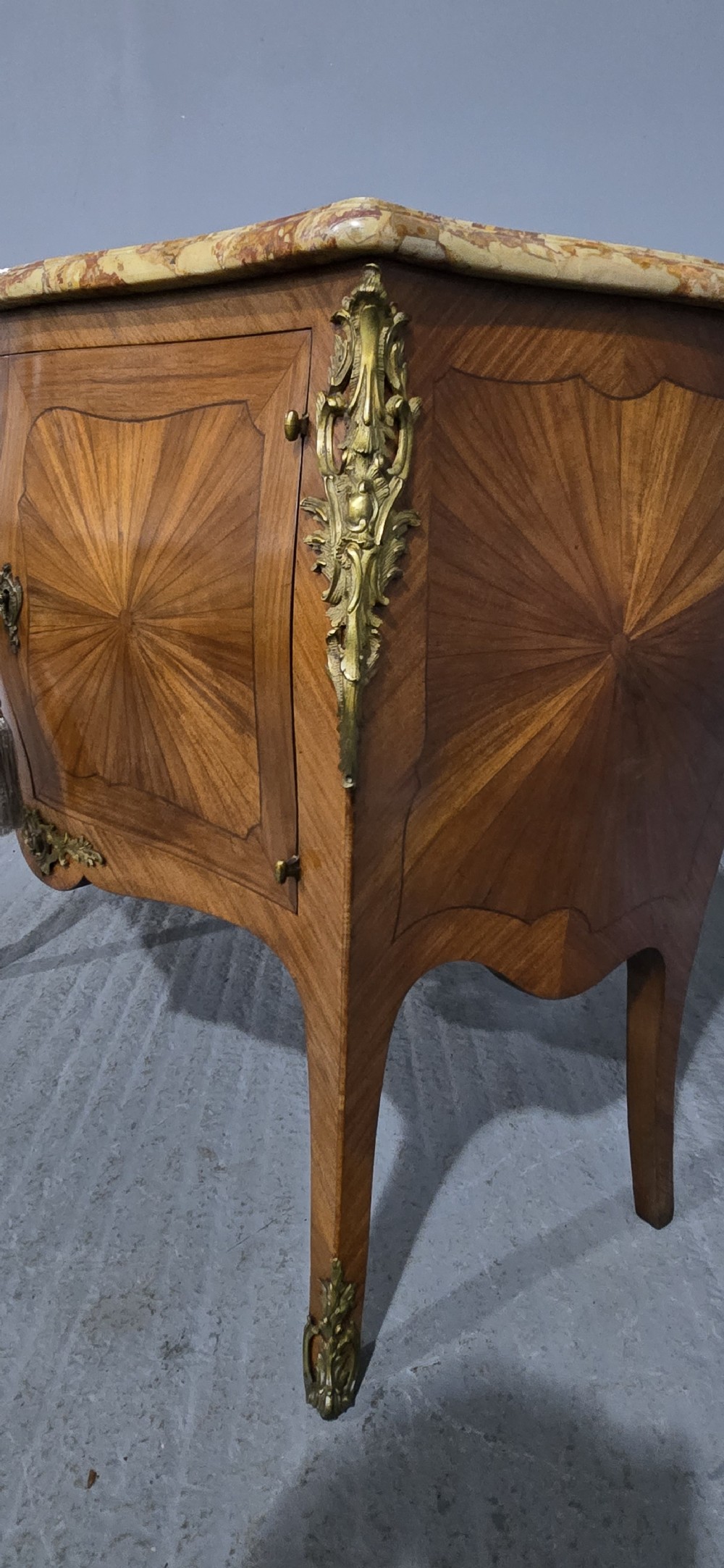 A French Louis XV style two-door cabinet featuring sunburst parquetry woodwork, a variegated marble top, cabriole legs, and ornate gilt bronze mounts. View VIII