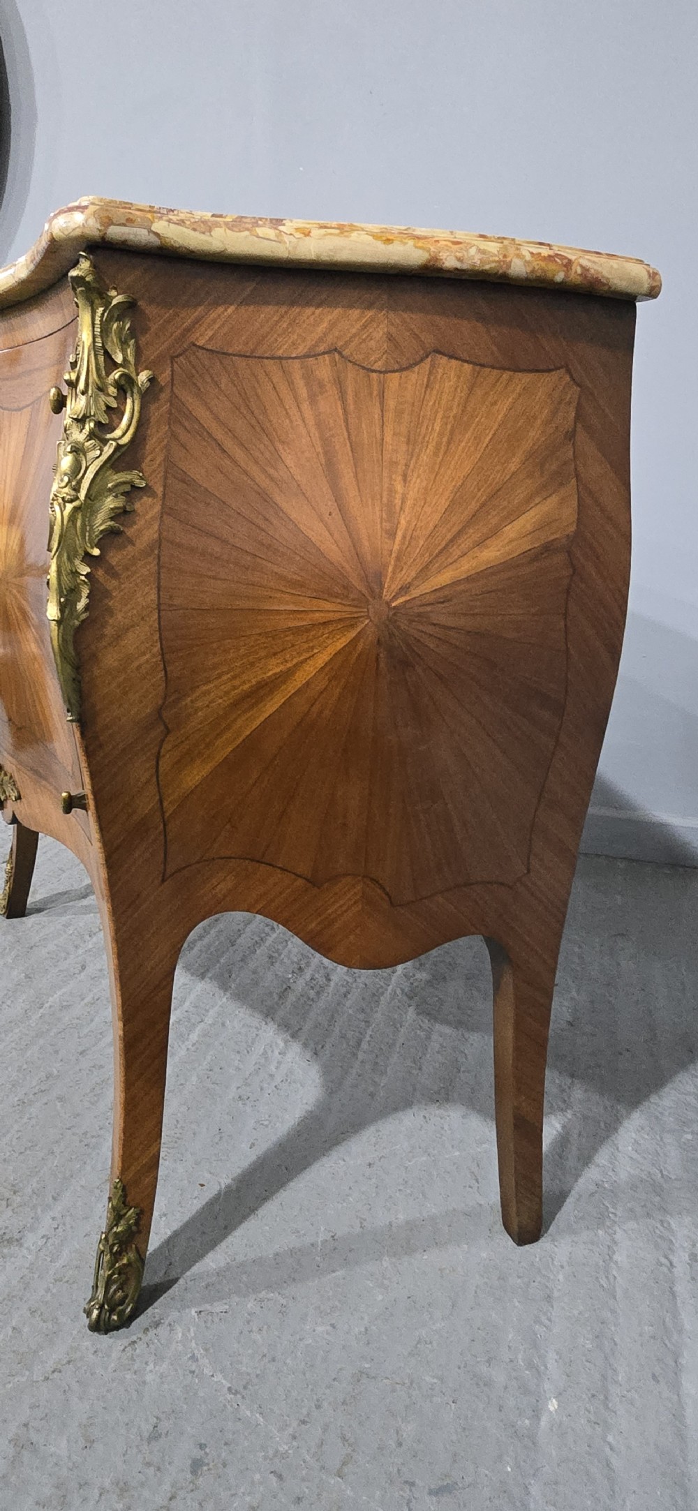 A French Louis XV style two-door cabinet featuring sunburst parquetry woodwork, a variegated marble top, cabriole legs, and ornate gilt bronze mounts. View X
