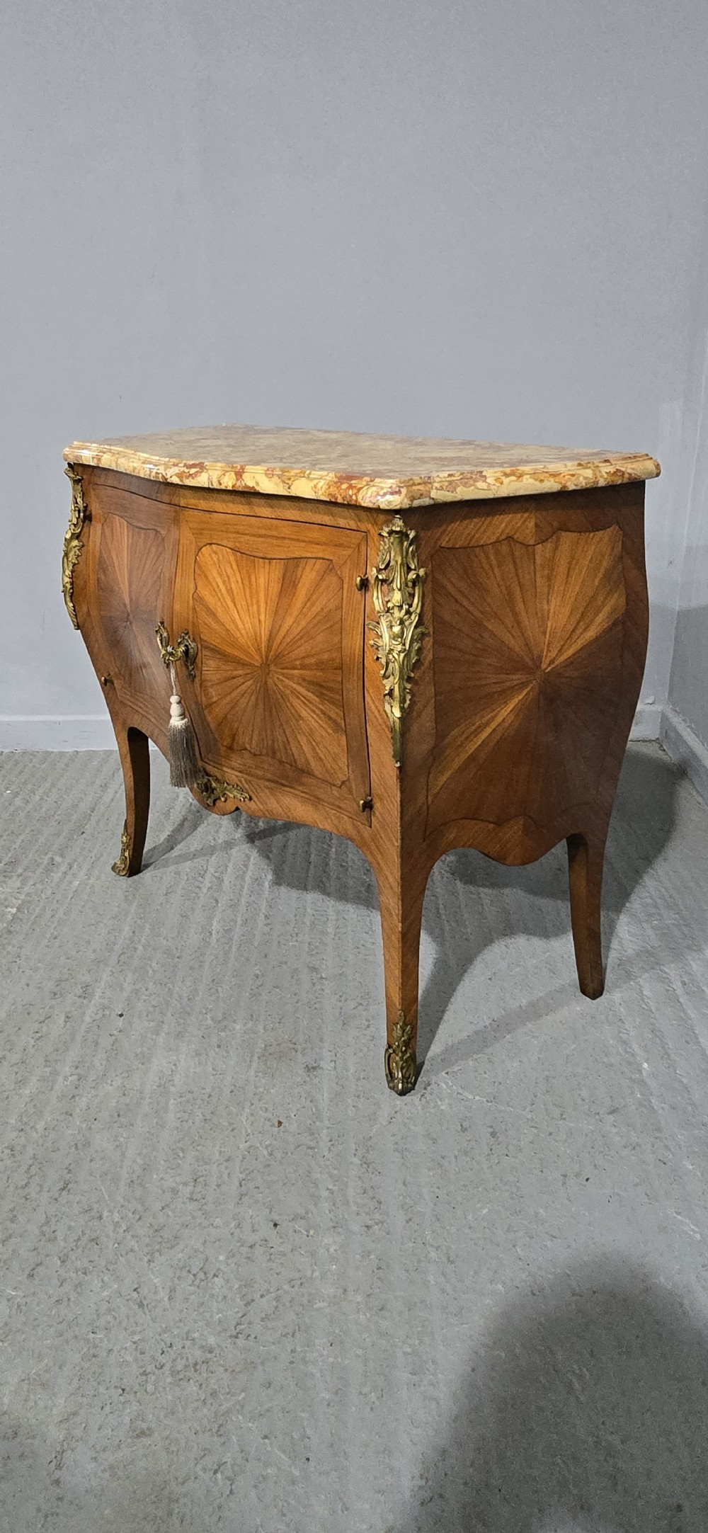 A French Louis XV style two-door cabinet featuring sunburst parquetry woodwork, a variegated marble top, cabriole legs, and ornate gilt bronze mounts. View XIII