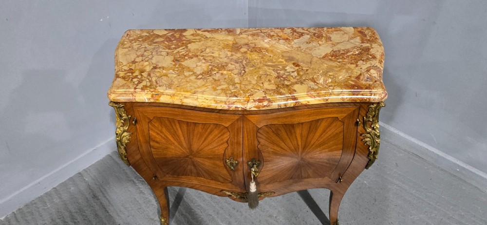 A French Louis XV style two-door cabinet featuring sunburst parquetry woodwork, a variegated marble top, cabriole legs, and ornate gilt bronze mounts. View XV