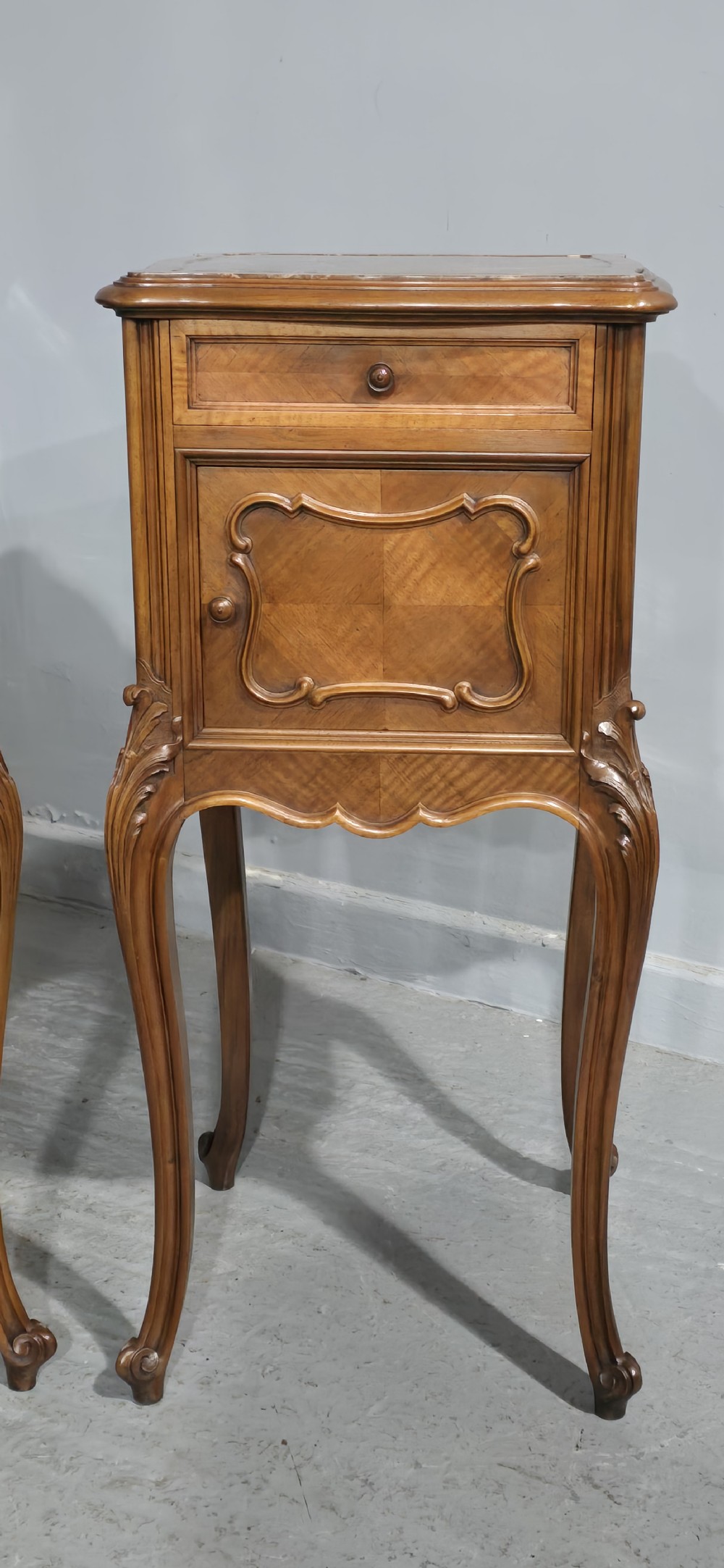 A pair of tall, slender French walnut bedside tables featuring marble tops, single upper drawers, panelled cupboard doors, and cabriole legs. View IV