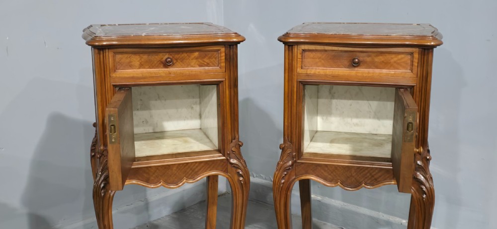 A pair of tall, slender French walnut bedside tables featuring marble tops, single upper drawers, panelled cupboard doors, and cabriole legs. View V