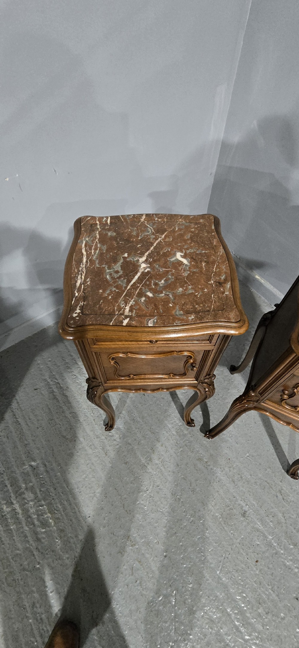 A pair of tall, slender French walnut bedside tables featuring marble tops, single upper drawers, panelled cupboard doors, and cabriole legs. View IX