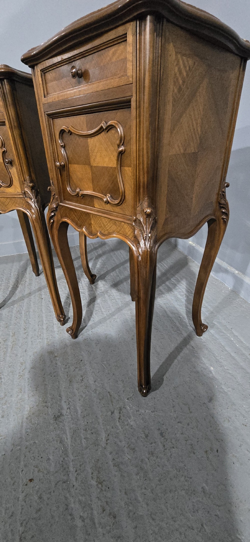 A pair of tall, slender French walnut bedside tables featuring marble tops, single upper drawers, panelled cupboard doors, and cabriole legs. View X