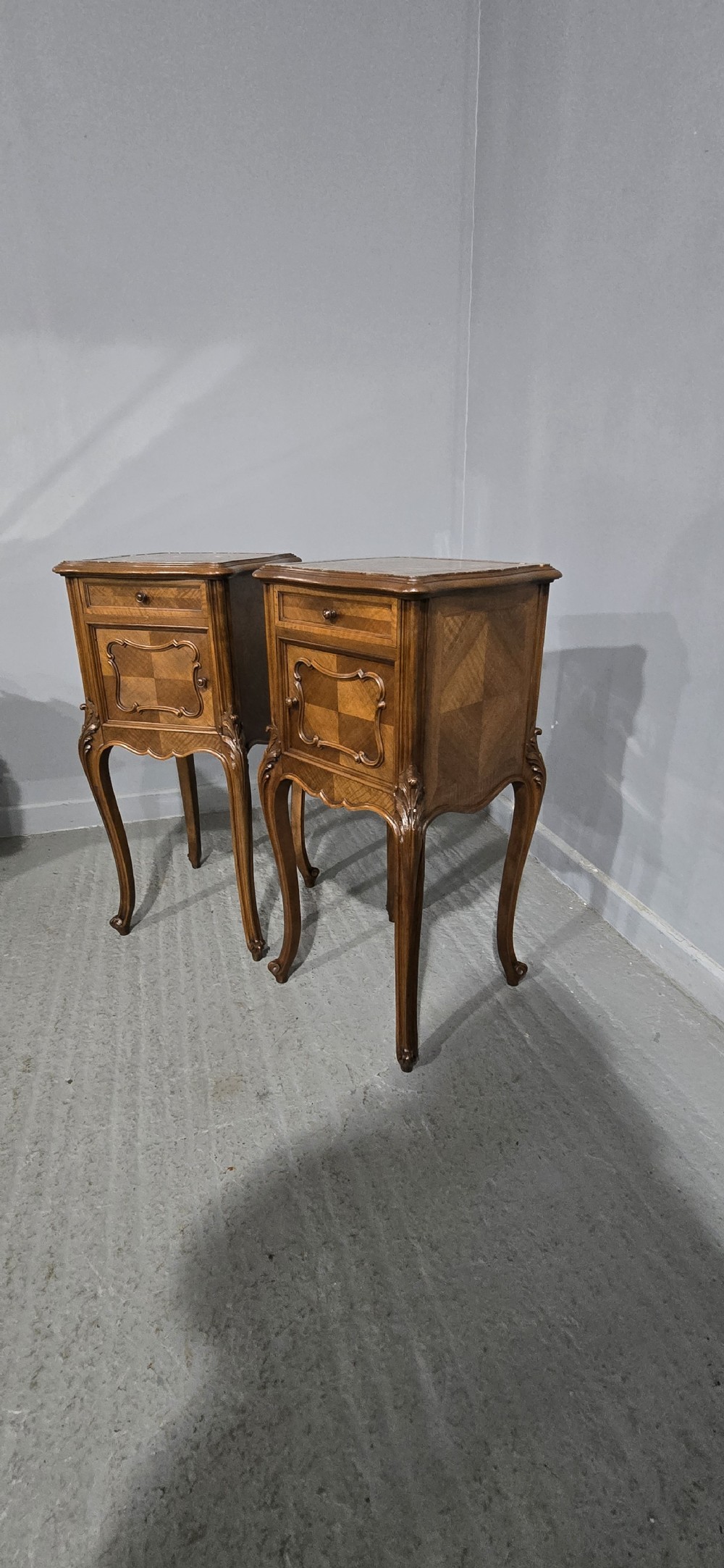 A pair of tall, slender French walnut bedside tables featuring marble tops, single upper drawers, panelled cupboard doors, and cabriole legs. View XI