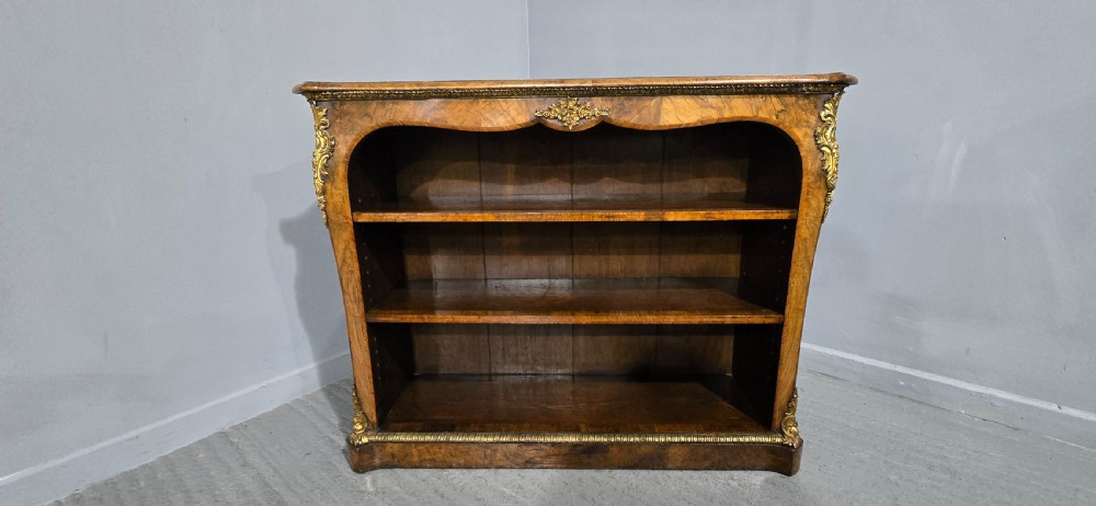 An antique open walnut library bookcase featuring three exposed shelves and decorative gilt bronze mounts along the upper apron and corner supports. View II