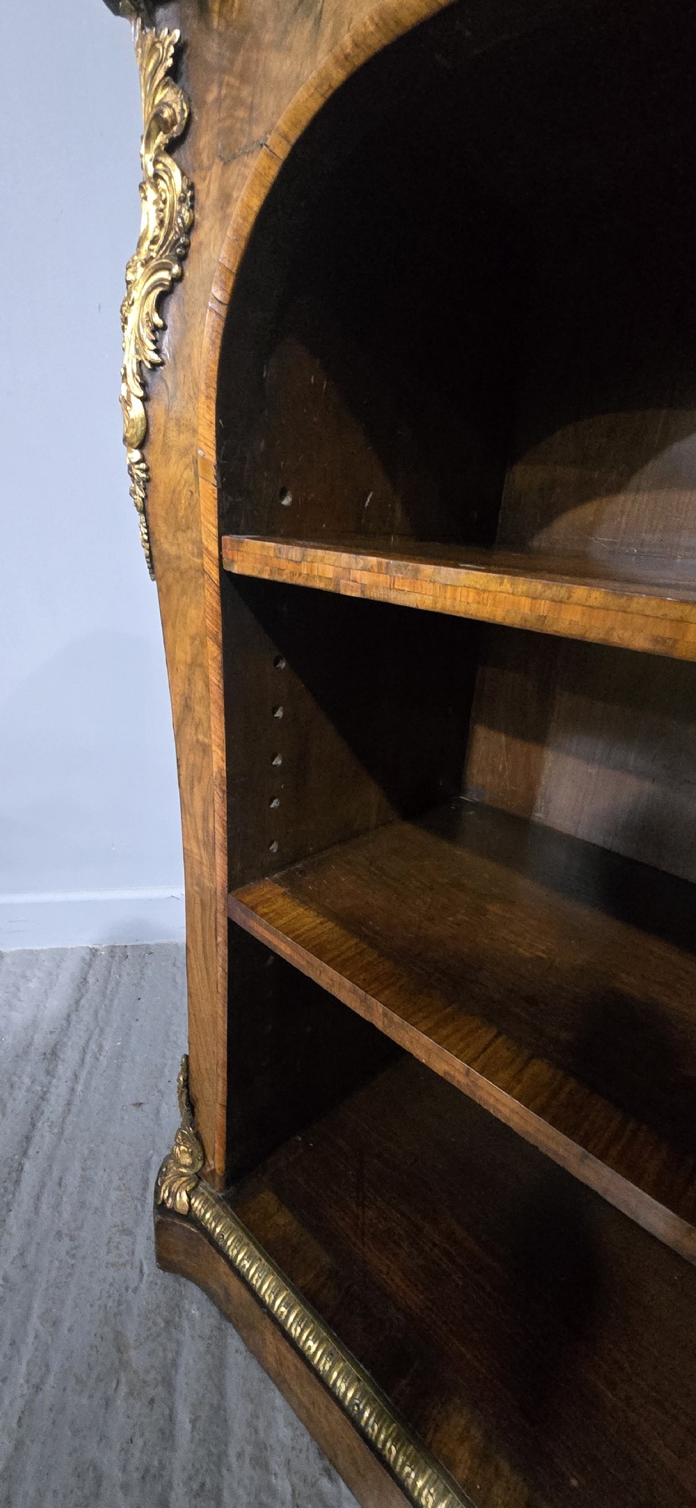 An antique open walnut library bookcase featuring three exposed shelves and decorative gilt bronze mounts along the upper apron and corner supports. View III