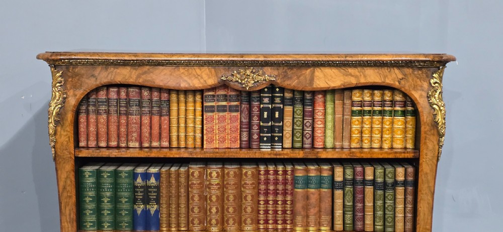 An antique open walnut library bookcase featuring three exposed shelves and decorative gilt bronze mounts along the upper apron and corner supports. View V