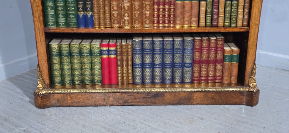 An antique open walnut library bookcase featuring three exposed shelves and decorative gilt bronze mounts along the upper apron and corner supports. View VI