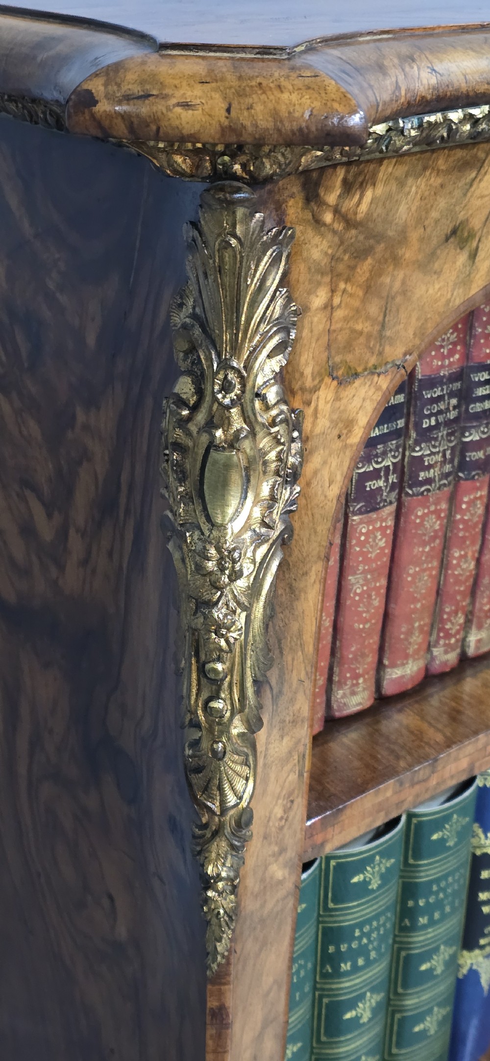 An antique open walnut library bookcase featuring three exposed shelves and decorative gilt bronze mounts along the upper apron and corner supports. View VIII