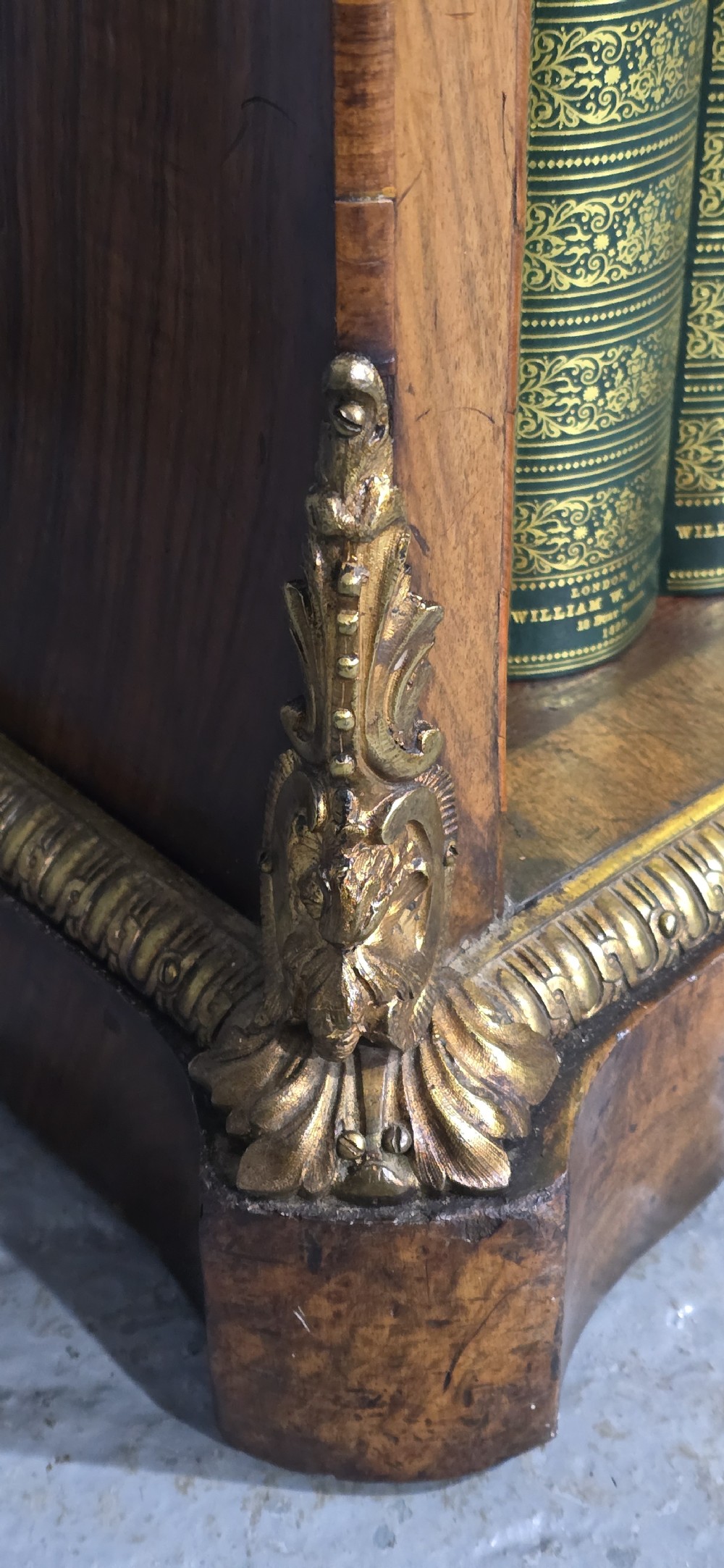 An antique open walnut library bookcase featuring three exposed shelves and decorative gilt bronze mounts along the upper apron and corner supports. View IX