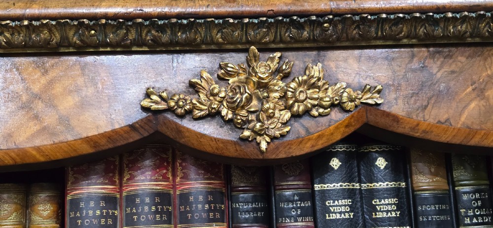 An antique open walnut library bookcase featuring three exposed shelves and decorative gilt bronze mounts along the upper apron and corner supports. View XII