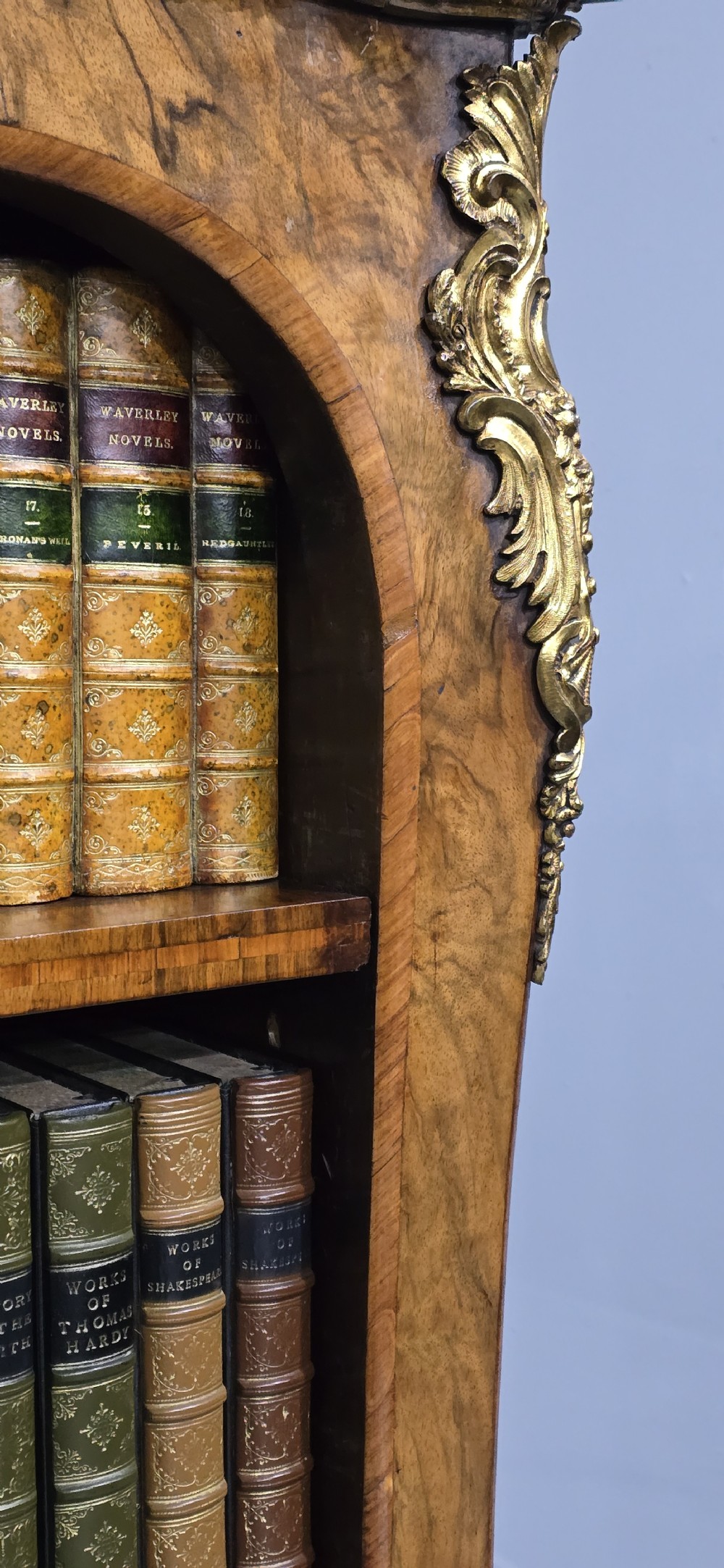 An antique open walnut library bookcase featuring three exposed shelves and decorative gilt bronze mounts along the upper apron and corner supports. View XIII