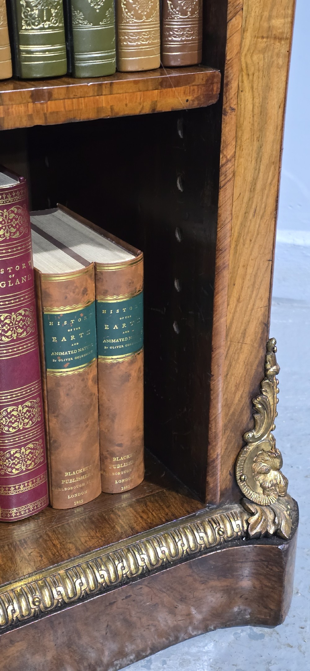 An antique open walnut library bookcase featuring three exposed shelves and decorative gilt bronze mounts along the upper apron and corner supports. View XIV