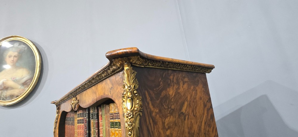 An antique open walnut library bookcase featuring three exposed shelves and decorative gilt bronze mounts along the upper apron and corner supports. View XVIII