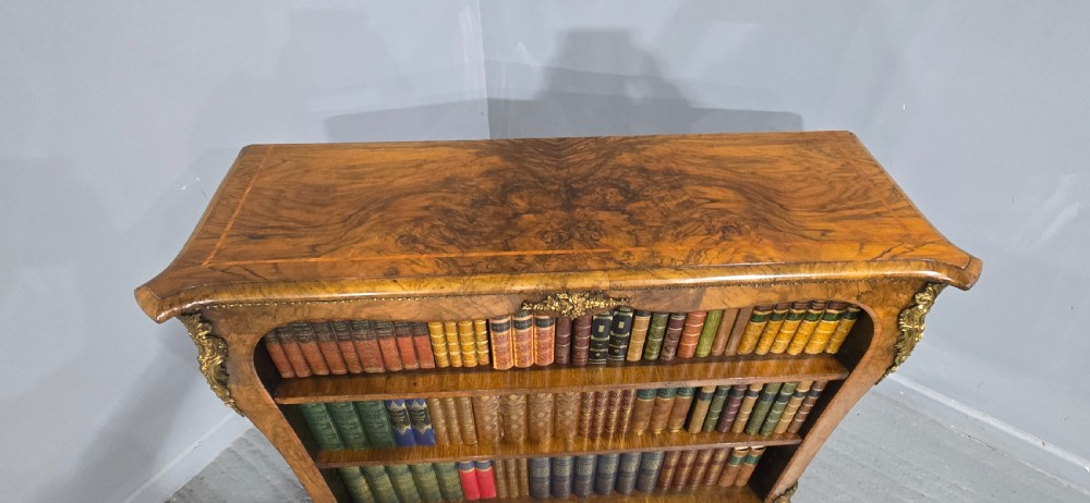 An antique open walnut library bookcase featuring three exposed shelves and decorative gilt bronze mounts along the upper apron and corner supports. View XIX