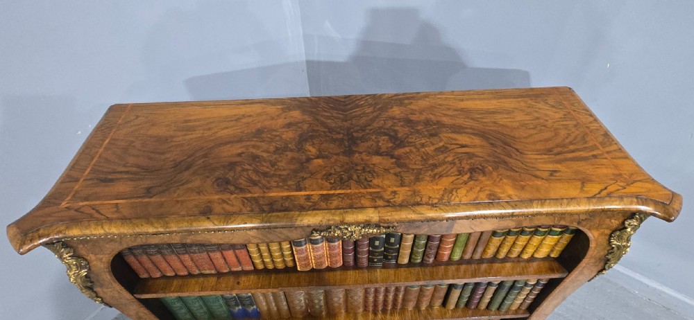 An antique open walnut library bookcase featuring three exposed shelves and decorative gilt bronze mounts along the upper apron and corner supports. View XX