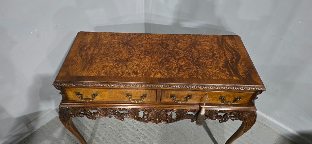 A burr walnut console table featuring two drawers with brass handles, a deeply carved apron with a central shell motif, and cabriole legs. View VIII