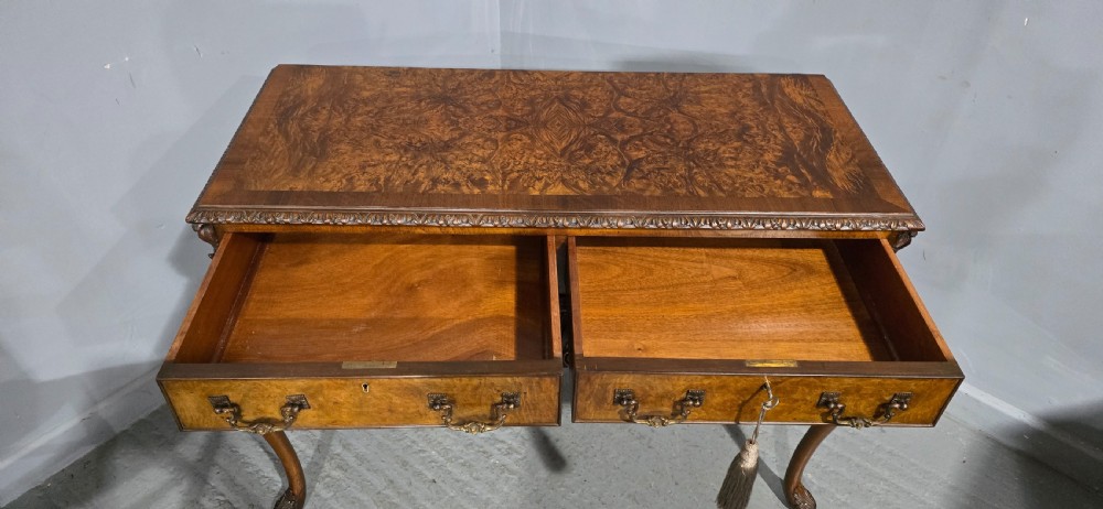 A burr walnut console table featuring two drawers with brass handles, a deeply carved apron with a central shell motif, and cabriole legs. View IX