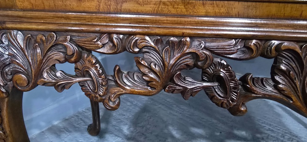 A burr walnut console table featuring two drawers with brass handles, a deeply carved apron with a central shell motif, and cabriole legs. View XI