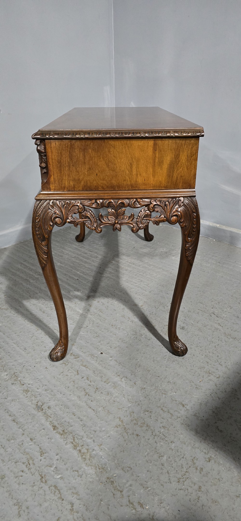 A burr walnut console table featuring two drawers with brass handles, a deeply carved apron with a central shell motif, and cabriole legs. View XIV