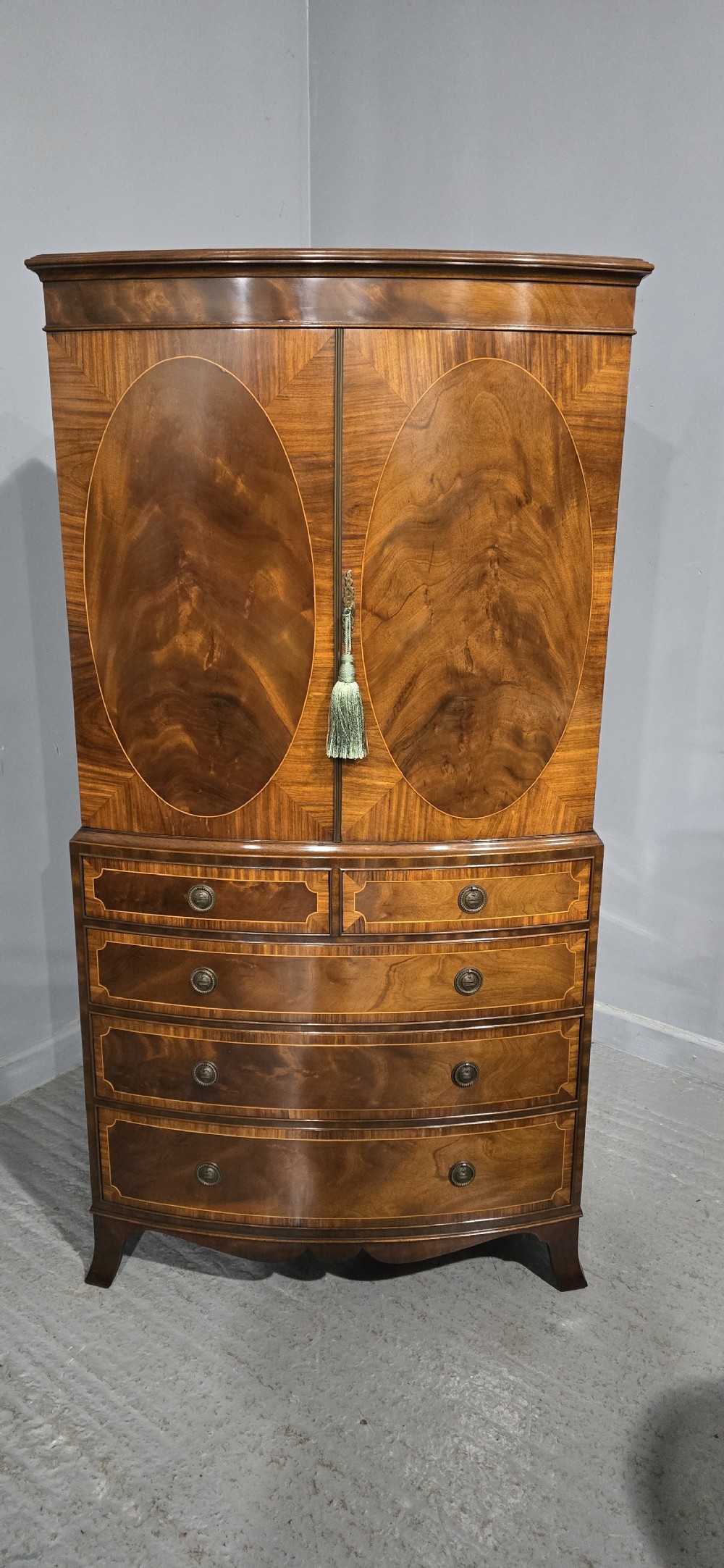 A Georgian mahogany bow-front linen press featuring oval flame mahogany inlay on the twin cupboard doors above four long graduated drawers. View III