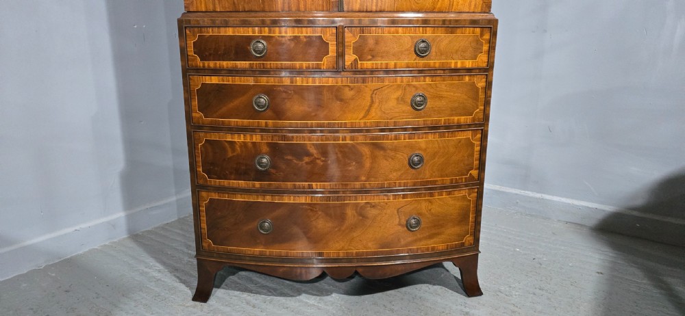 A Georgian mahogany bow-front linen press featuring oval flame mahogany inlay on the twin cupboard doors above four long graduated drawers. View IV