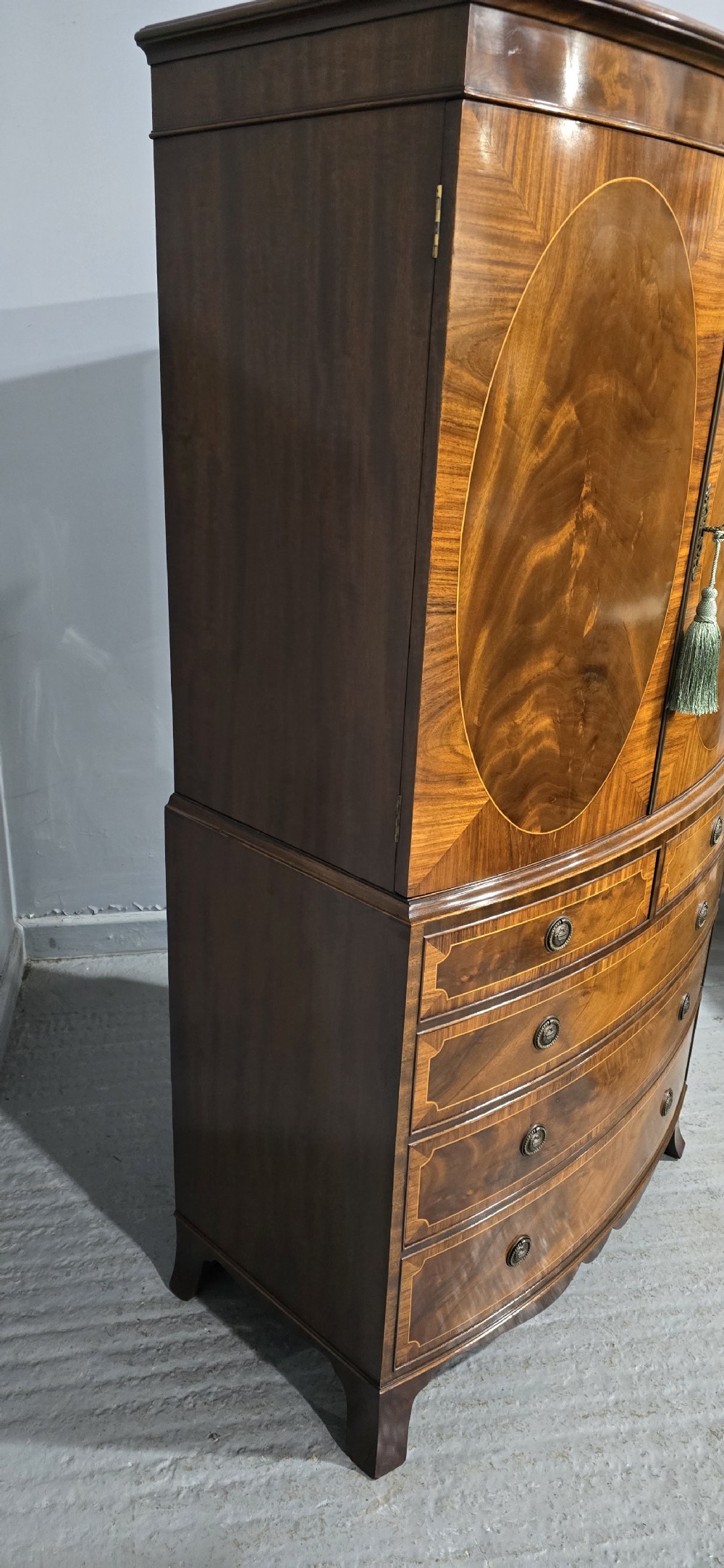 A Georgian mahogany bow-front linen press featuring oval flame mahogany inlay on the twin cupboard doors above four long graduated drawers. View VII