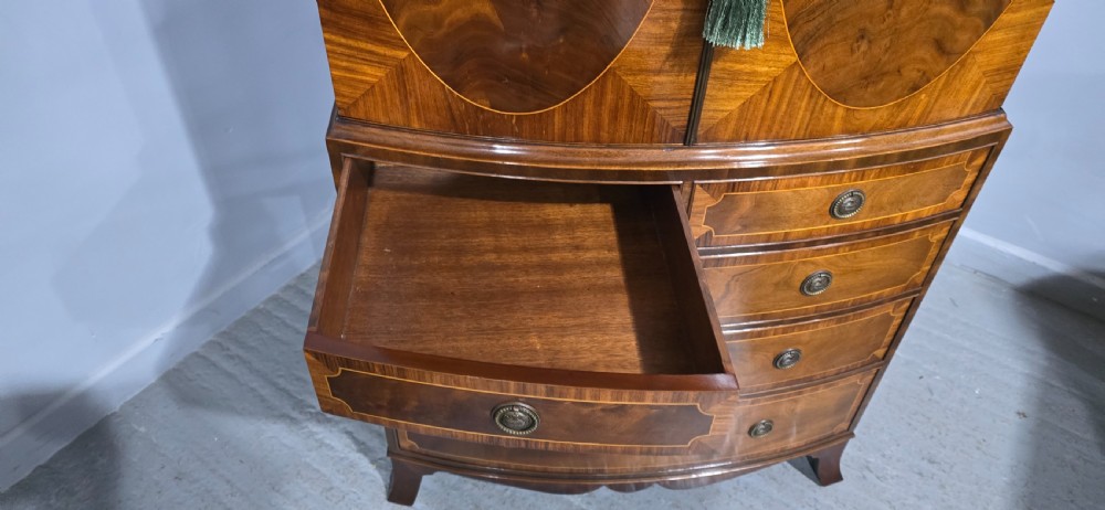 A Georgian mahogany bow-front linen press featuring oval flame mahogany inlay on the twin cupboard doors above four long graduated drawers. View VIII