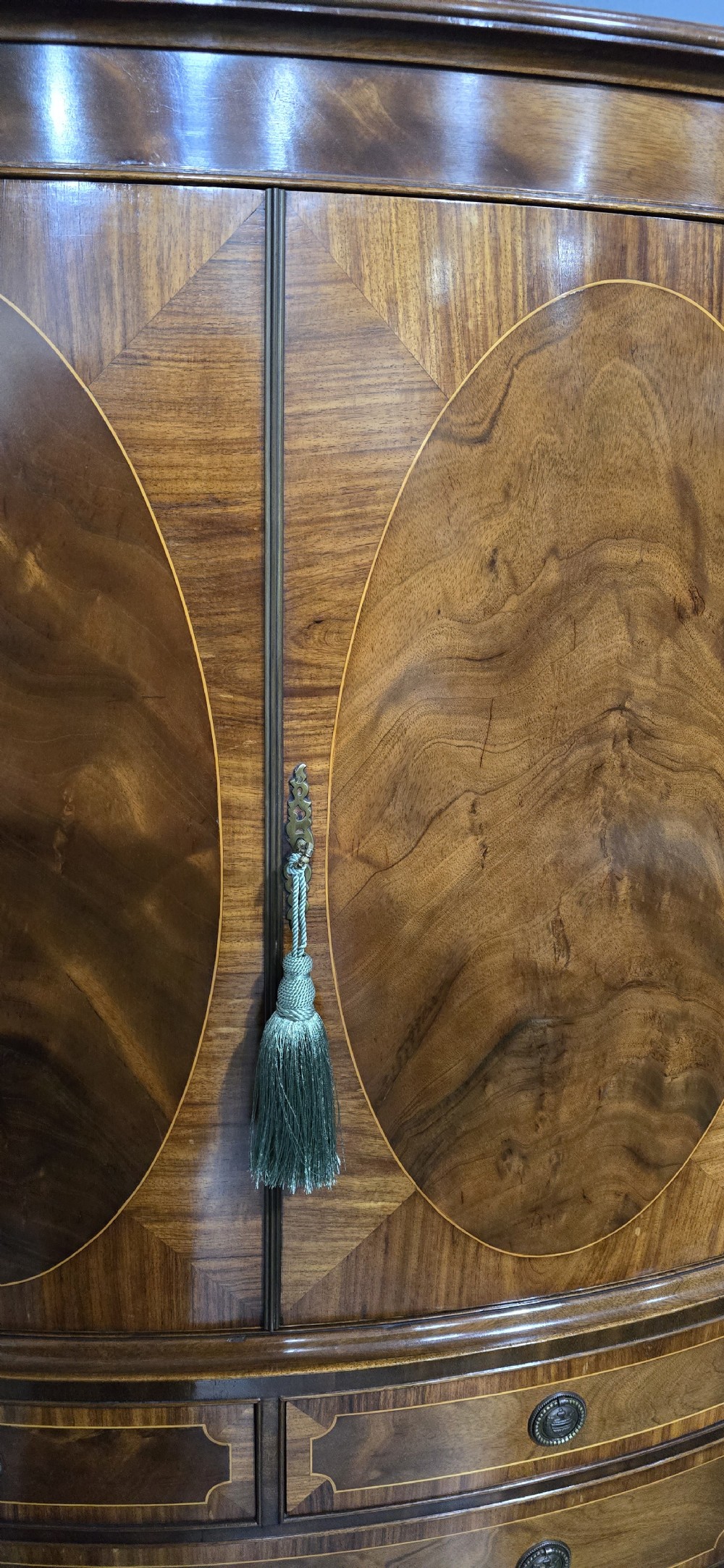 A Georgian mahogany bow-front linen press featuring oval flame mahogany inlay on the twin cupboard doors above four long graduated drawers. View IX
