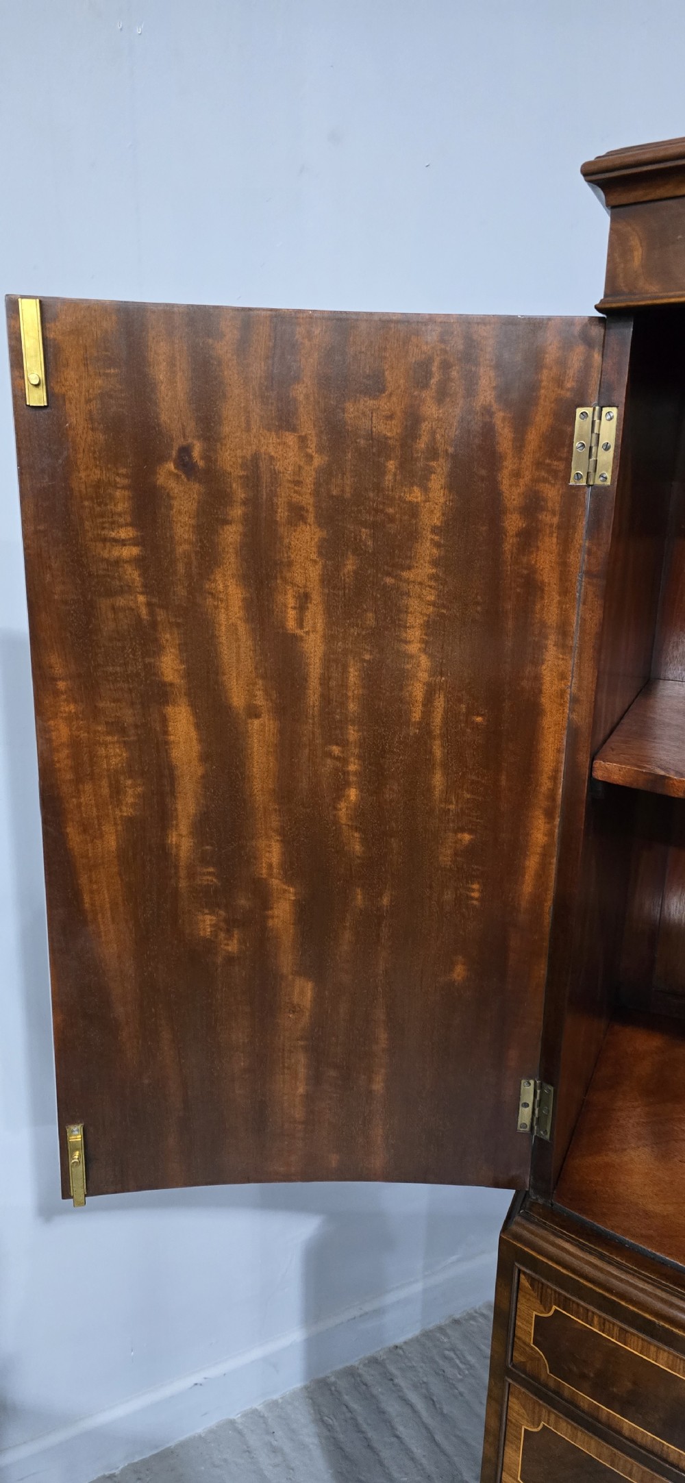 A Georgian mahogany bow-front linen press featuring oval flame mahogany inlay on the twin cupboard doors above four long graduated drawers. View XI