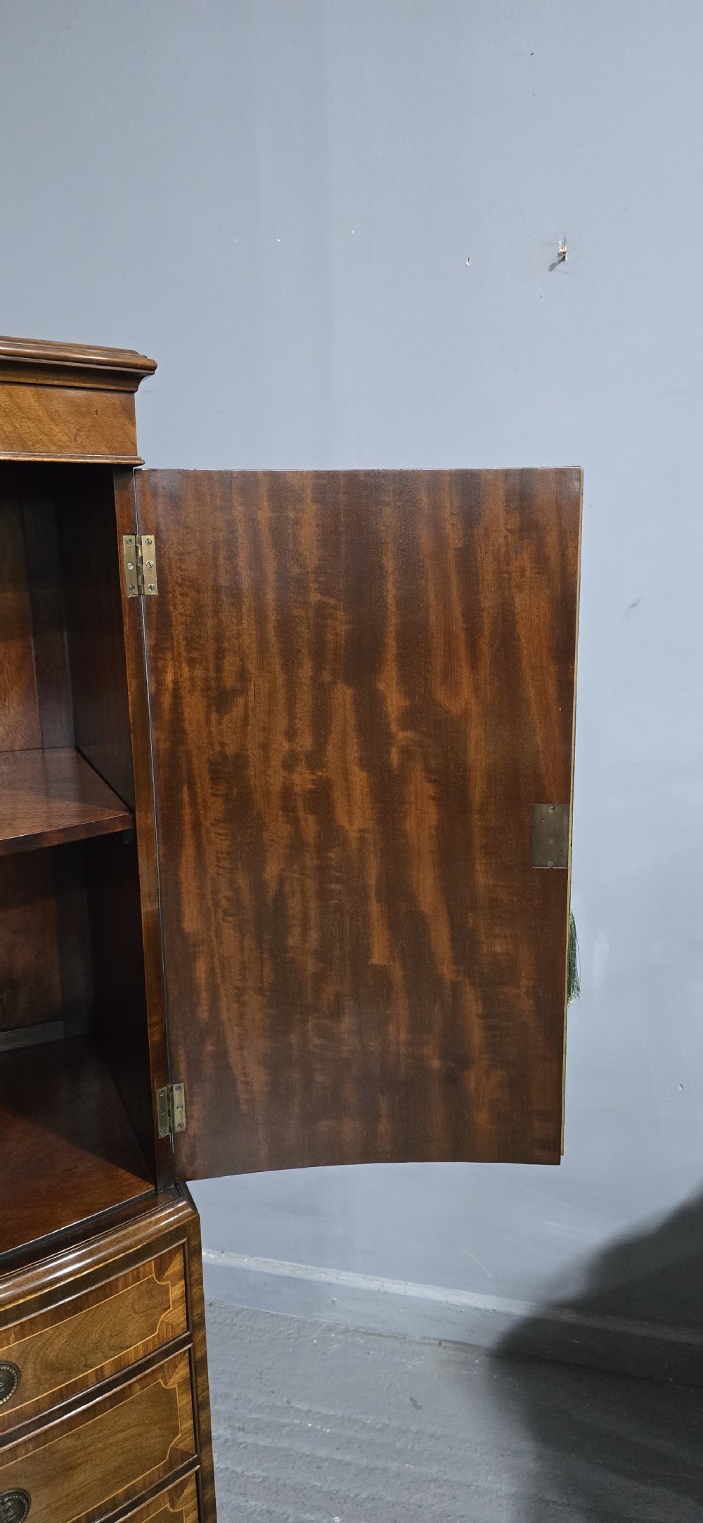 A Georgian mahogany bow-front linen press featuring oval flame mahogany inlay on the twin cupboard doors above four long graduated drawers. View XII