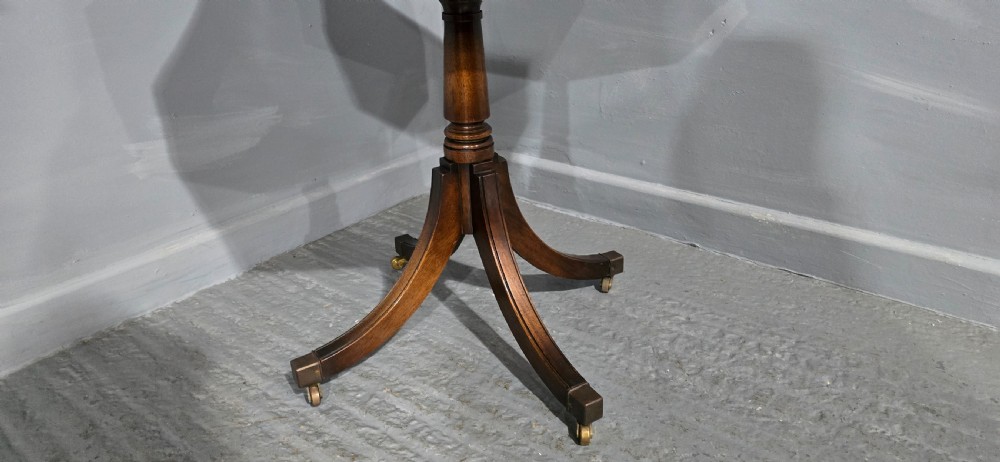 An octagonal mahogany campaign drum table with a gilt-tooled brown leather insert top, brass corner mounts, a single frieze drawer, and a four-legged pedestal base with brass castors. View III
