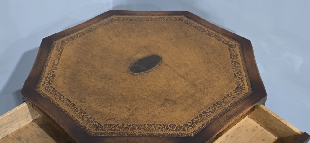 An octagonal mahogany campaign drum table with a gilt-tooled brown leather insert top, brass corner mounts, a single frieze drawer, and a four-legged pedestal base with brass castors. View VII
