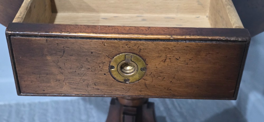 An octagonal mahogany campaign drum table with a gilt-tooled brown leather insert top, brass corner mounts, a single frieze drawer, and a four-legged pedestal base with brass castors. View XI