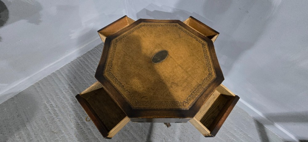An octagonal mahogany campaign drum table with a gilt-tooled brown leather insert top, brass corner mounts, a single frieze drawer, and a four-legged pedestal base with brass castors. View XII